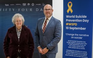 A man and a woman standing in front of a poster