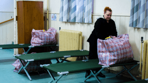 A lady unpacking a bag on a bed at the night shelter