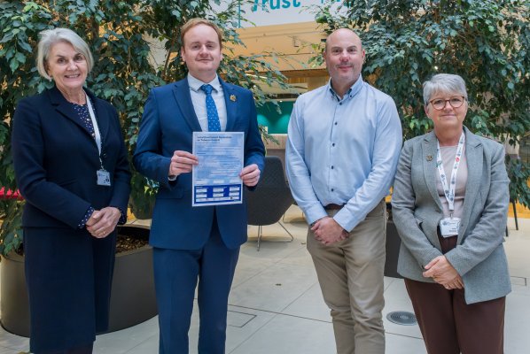 Two men and two women holding a paper pledge