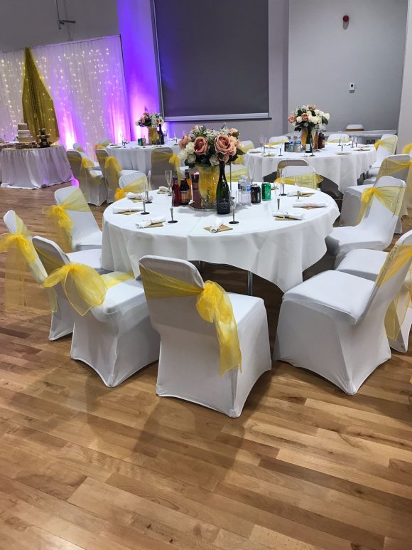 white table, chairs with yellow ribbons, flowers on table